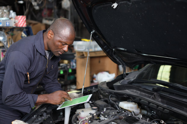 在修车站，穿着制服的汽车技师拿着平板电脑检查、保养汽车。
汽车维修服务理念图片下载