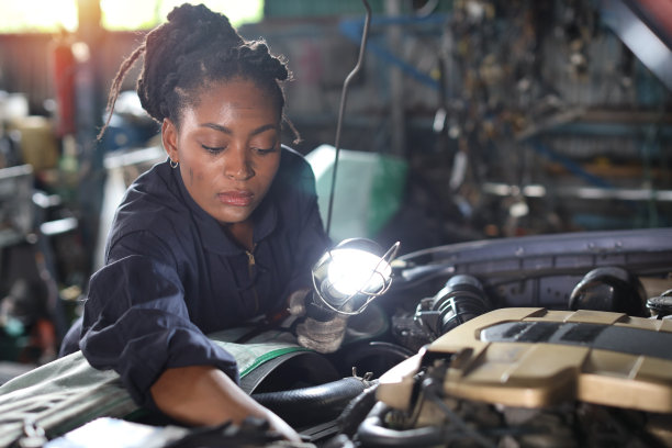穿制服的女技师在修车站检查保养车服务。工人拿着手电筒和扳手修理损坏的车辆。汽车中心维修服务理念。图片下载