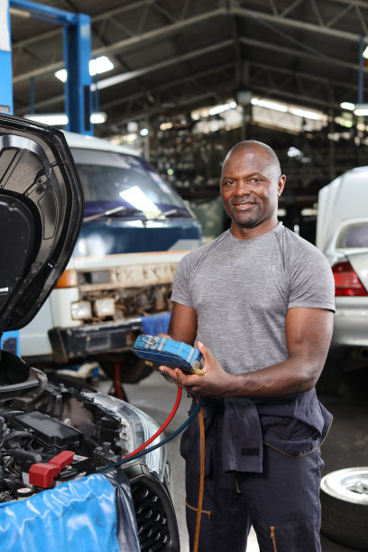 机械师半制服检查汽车空调系统制冷剂充注、检漏、充注制冷剂服务。汽车中心维修服务理念。图片下载