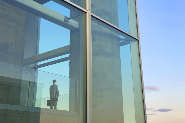 商人望向窗外的现代办公大楼图片下载