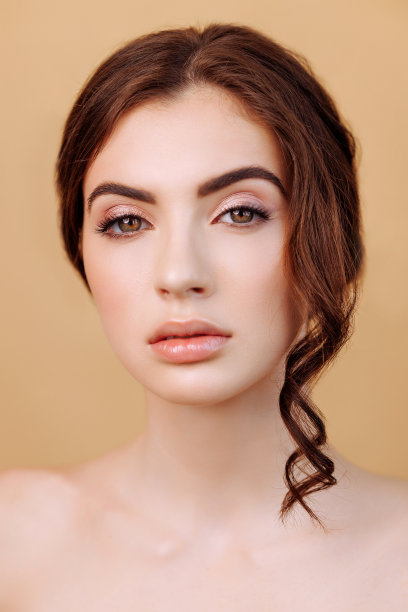 美丽的女人的肖像看着相机孤立的米色背景。图片下载