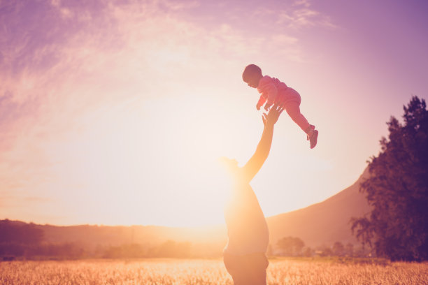 剪影父亲带着孩子在空中玩耍，在夕阳的映衬下捕捉画面图片下载