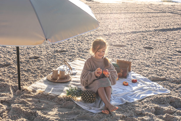 小女孩在沙滩上野餐和水果。图片下载