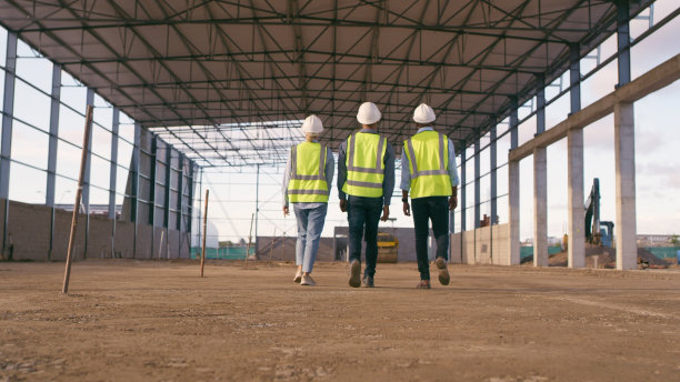 人们，建筑师和行走在建筑工地规划，协作或团队合作。工程师、建造者或承包商讨论工业建筑的团队项目计划图片下载