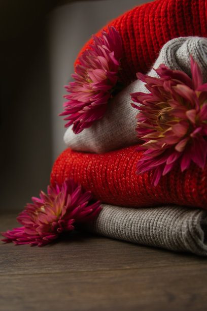 彩色针织毛衣的图案特写。手工美利奴羊毛产品。一叠叠着的衣服和鲜花。图片下载