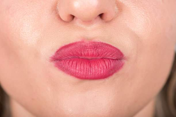 女人的脸和吻符号与嘴唇。摄影棚照片拍摄。使用亮红色唇膏。图片下载