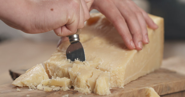 女人的手在切硬的帕尔马干酪图片下载