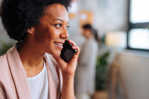 非裔美国妇女一边接电话一边微笑的侧面头像。图片下载