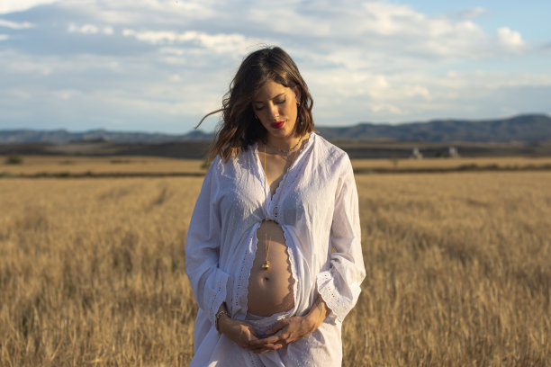 一个年轻的孕妇在阴天的乡下享受图片下载