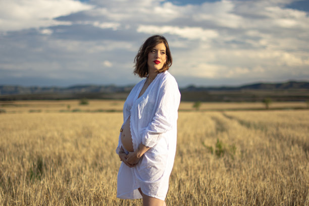 一个年轻的孕妇在阴天的乡下享受图片下载