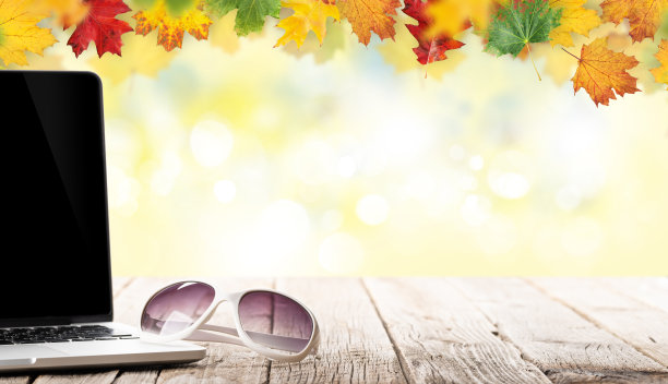 在秋天的背景前，木桌上放着笔记本电脑和太阳镜图片下载