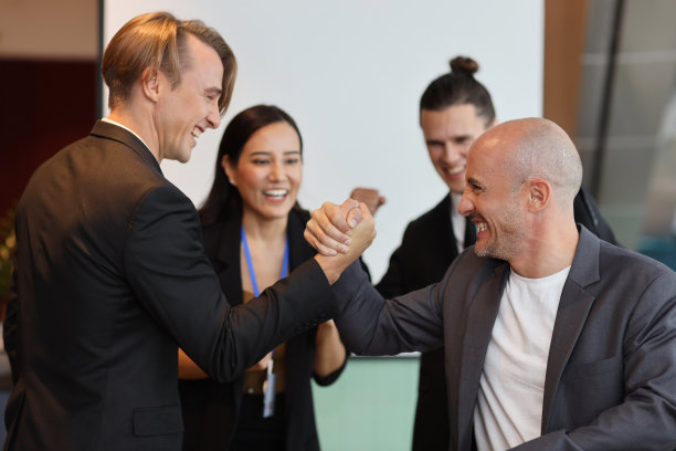 年轻的多民族专业商人在合作过程中掰手腕，签下新的商业合同后脸上带着开心的笑容。同事和一起工作的概念图片下载