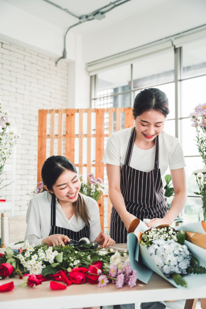在花店里，两个漂亮的花匠正在精心地整理一束准备送给客户的鲜花。图片下载