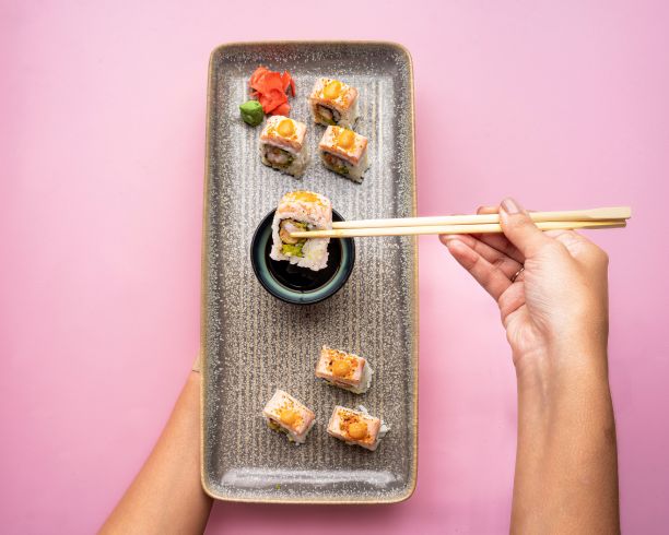 粉红色背景上的寿司卷板的俯视图图片下载
