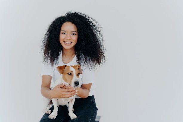 一名头发清爽的开朗女子与一只纯种狗玩耍并摆姿势，捕捉了一个难忘的时刻。人和动物的概念。图片下载