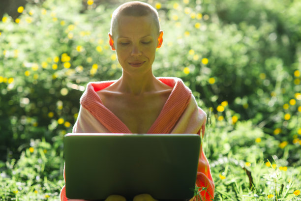 时髦的短发女人在户外用笔记本电脑工作。自由职业者，远程工作。图片下载