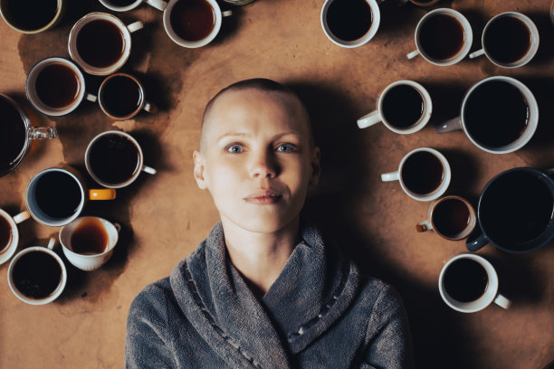 女人被许多杯咖啡包围着。一个短发的女人正看着镜头。截止日期，加班的概念。图片下载