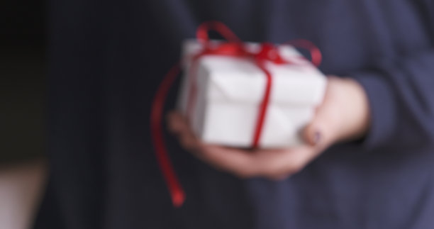 失焦的年轻女孩带着白色的红丝带礼盒图片下载