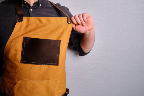 一个穿着厨房围裙的男人。厨师从事烹饪工作。穿着制服和防护服。食品服务方面的工作。专业烹饪。绿色面料围裙，休闲时尚服装。英俊的面包师摆姿势图片下载