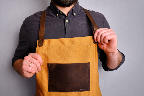 一个穿着厨房围裙的男人。厨师从事烹饪工作。穿着制服和防护服。食品服务方面的工作。专业烹饪。绿色面料围裙，休闲时尚服装。英俊的面包师摆姿势图片下载