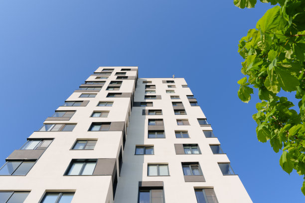 现代公寓大楼在一个阳光明媚的日子。蓝天映衬下的绿树和住宅楼图片下载