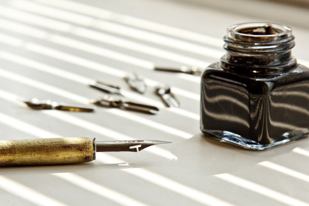 有金属笔尖的墨水瓶，在太阳光线的白色背景上。白色办公桌上的文具近距离俯视图。拼写课和书法练习。模板，布局，背景图片下载