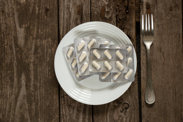 午餐时，桌上的白色盘子里装着白色药片图片下载