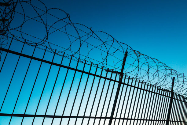 有倒刺的铁丝围成一片封闭的区域，对着天空。图片下载