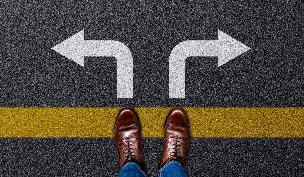 商人站在柏油路上，拿着左右方向的箭头。观念是商人的选择、决定图片下载