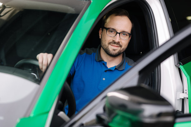 机械师透过打开的车门望向镜头的照片。戴眼镜的人在测试电子设备。验车理念图片下载