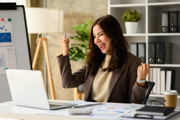 兴奋的千禧一代女性创业公司创始人看着笔记本电脑屏幕，庆祝商业成功。图片下载