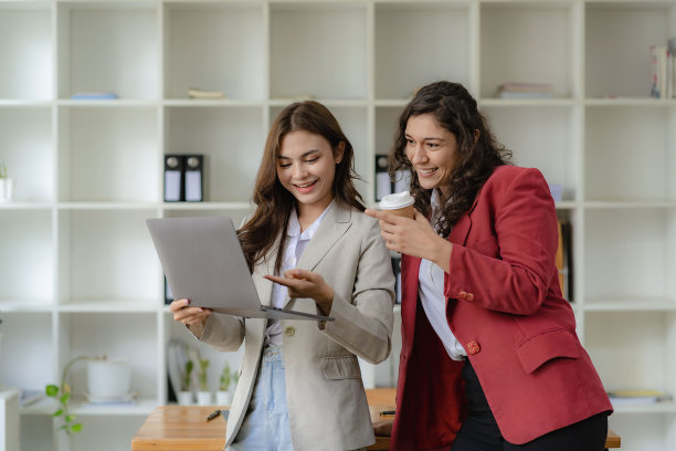 两个年轻的女商人和会计谈论笔记本电脑和平板电脑两个有吸引力的千禧一代白人女商人正在一起计划他们的项目。图片下载