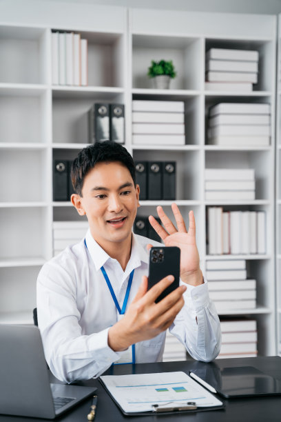 快乐的商人拿着手机看着屏幕挥手视频呼叫朋友在线移动聊天应用使用智能手机视频聊天应用。图片下载