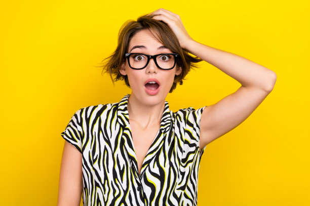 少女可爱的漂亮女人的肖像，短发，条纹衬衫，眼镜，手臂放在头上，孤立在黄色背景图片下载