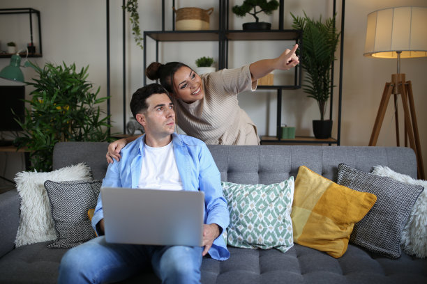 微笑的夫妇在家里放松笔记本电脑，肖像。库存图片图片下载