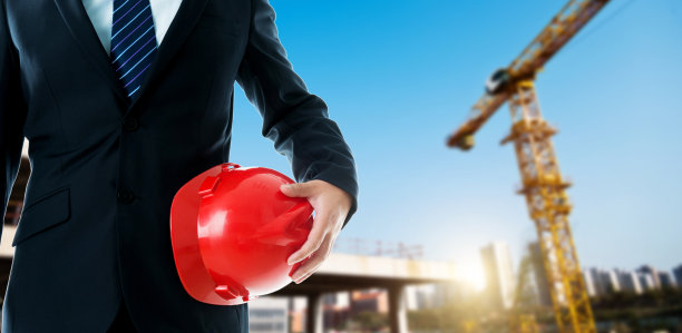 商人站着，拿着一顶红色安全帽图片下载