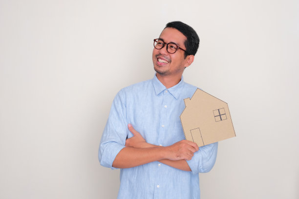 一个成年男子带着快乐的表情望向右边，手里拿着一个房子形状的纸板图片下载