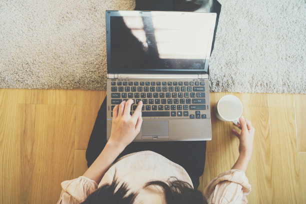 俯视图妇女手指打字的笔记本电脑坐在房子的地板上图片下载