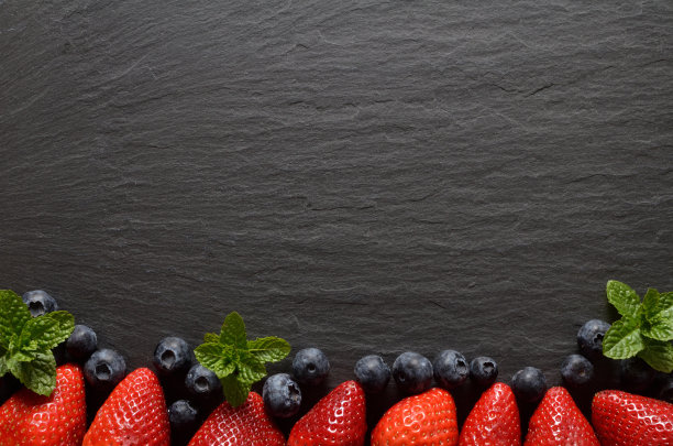 草莓、蓝莓和新鲜薄荷叶铺在复古石板上。俯视图，copyspace。图片下载