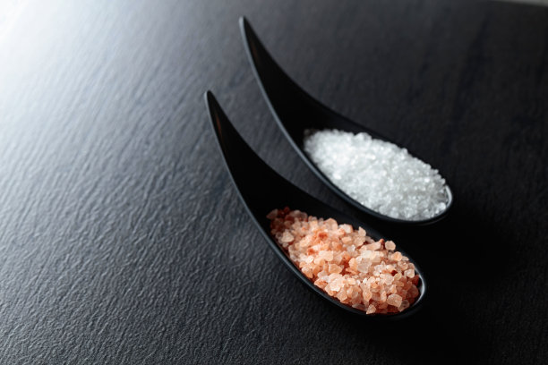 黑色的桌子上放着白色的海盐和粉红色的喜马拉雅盐。图片下载