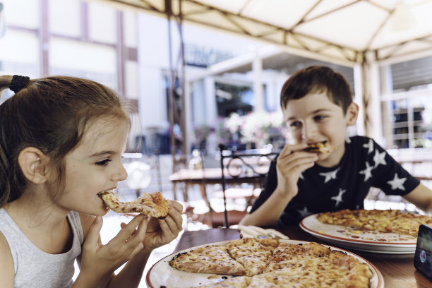 哥哥和妹妹在餐厅吃披萨。披萨。孩子的肖像图片下载