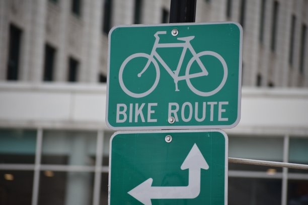 自行车道绿色金属标志指向城市街道上的自行车道图片下载