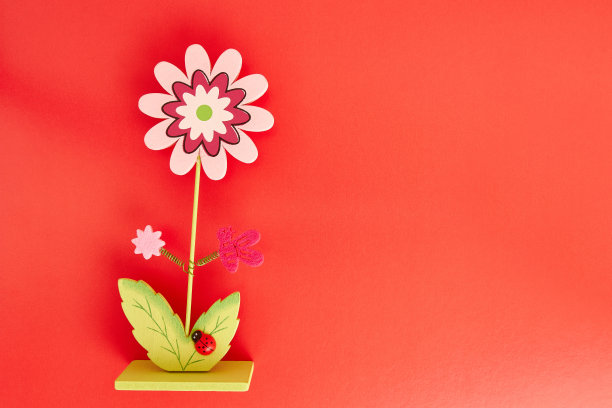 复活节餐桌上红色背景上洋甘菊形状的木制装饰品。复活节庆祝活动。图片下载
