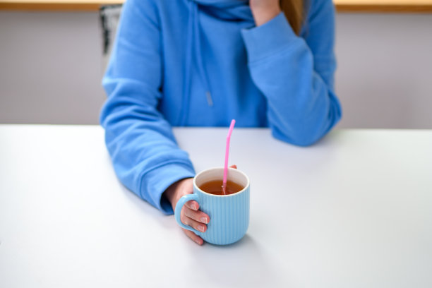 用塑料吸管从杯子里喝一杯温暖的红茶图片下载