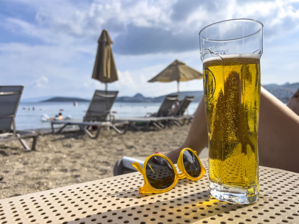 一杯冰啤酒在海滩上冒着泡泡图片下载