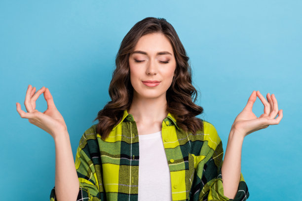 照片中可爱可爱的女子穿着格子衬衫闭着眼睛练习瑜伽孤立的蓝色背景图片下载