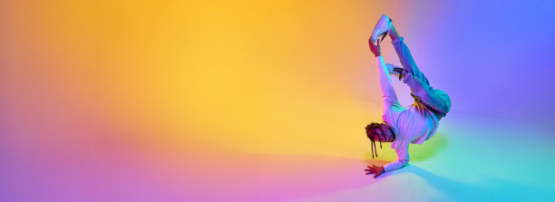 富有表现力的年轻人穿着运动服跳霹雳舞，在霓虹灯的渐变多色工作室背景下跳嘻哈舞图片下载