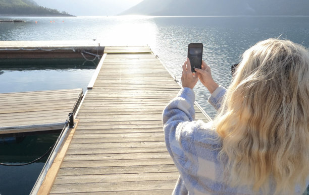 一位老妇人沿着木制的湖码头散步图片下载