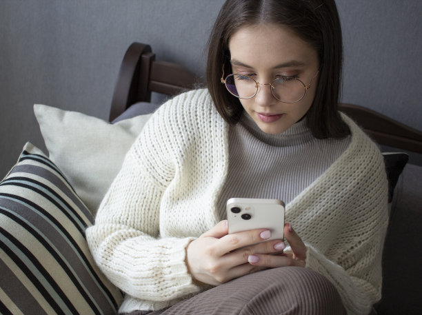 一个女孩穿着一件暖和的开襟羊毛衫坐在沙发上写留言图片下载
