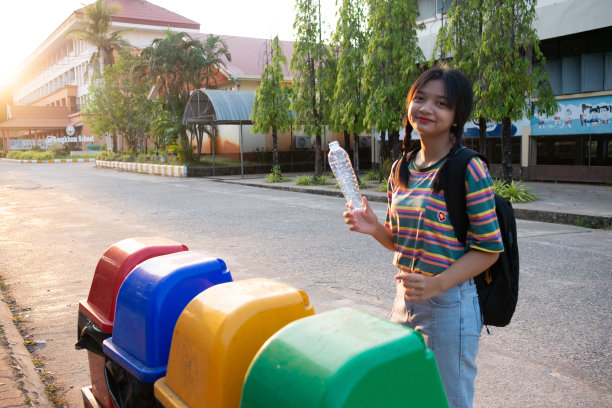 学生们把塑料瓶扔在学校的垃圾桶里。图片下载
